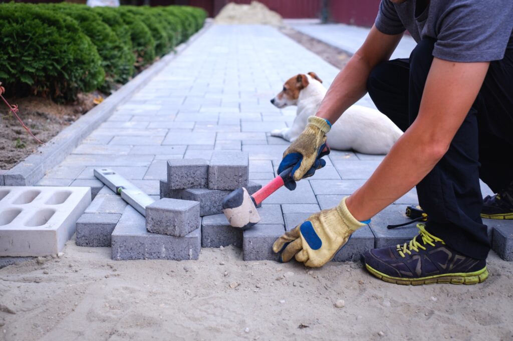 The master in yellow gloves lays paving stones