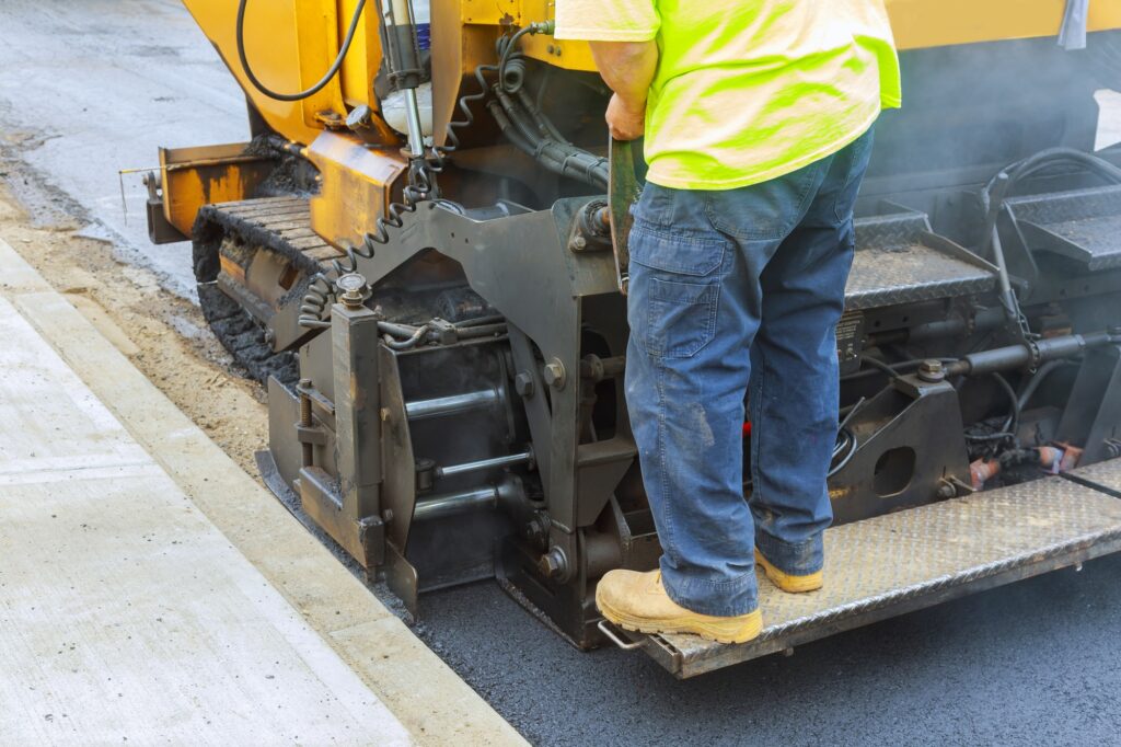 Workers making asphalt with shovels at road construction paving a road